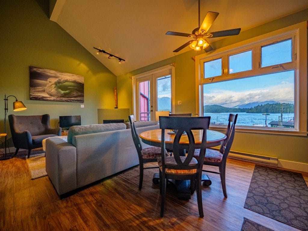 A cozy living and dining area with green walls, modern furniture, and large windows is perfect for capturing stunning sunset views of the lake and mountains with the best Airbnb cameras.